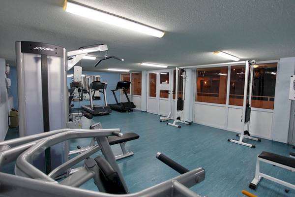 Fitnessbereich im DIT Evrika Beach Club mit Laufbändern, Kraftgeräten und Fenstern.