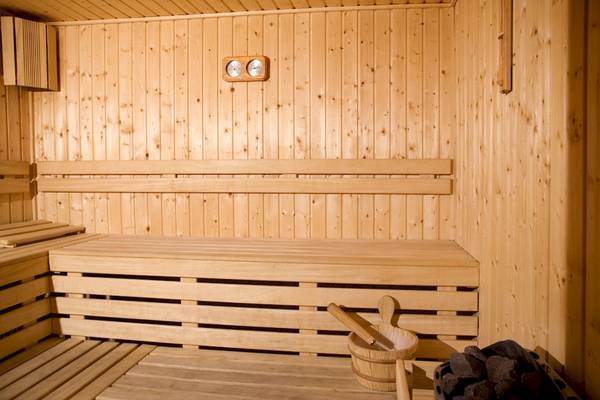Innenansicht der Sauna des DIT Evrika Beach Clubs mit Holzwänden, Bänken und Thermometer.