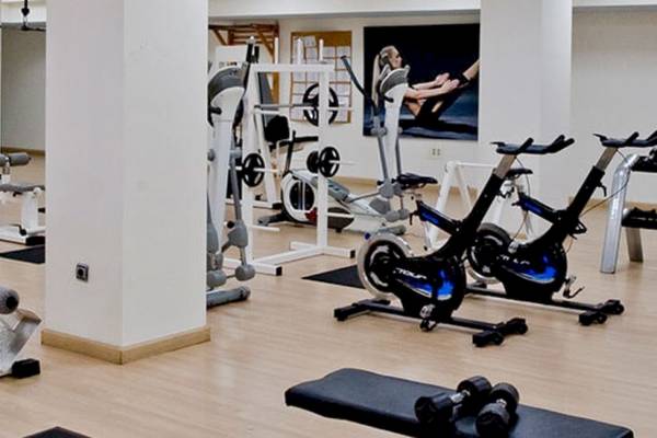 Fitnessstudio im Alexandre Hotel Gala mit verschiedenen Trainingsgeräten und einer Wand mit einem Fitnessposter.