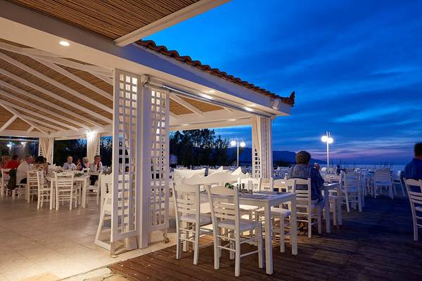 Terrassenrestaurant des Mythos Palace Resort & Spa bei Nacht mit Gästen an Tischen