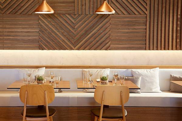 Innenbereich des Daios Cove Luxury Resort & Villas Restaurant mit Sitzecke, Holzwänden und heller Beleuchtung.