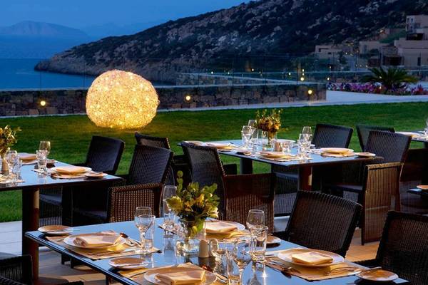 Außenbereich des Daios Cove Luxury Resort & Villas mit Esstischen und Meerblick bei Nacht