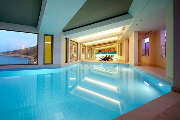 Innenpool des Daios Cove Luxury Resort & Villas mit Meerblick und Loungebereich