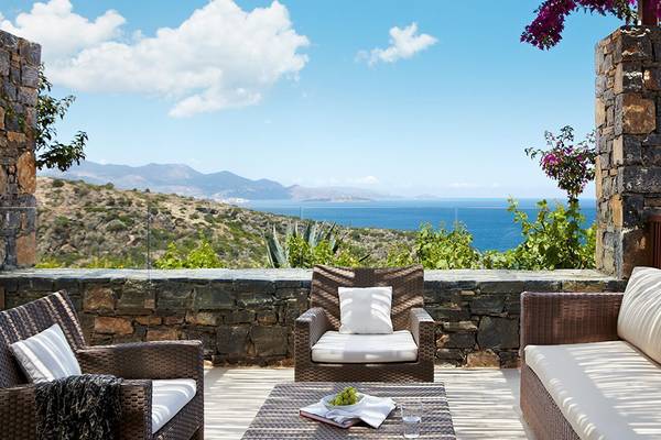 Außenterrasse des Daios Cove Luxus Resorts mit Blick auf das Meer und Berge.