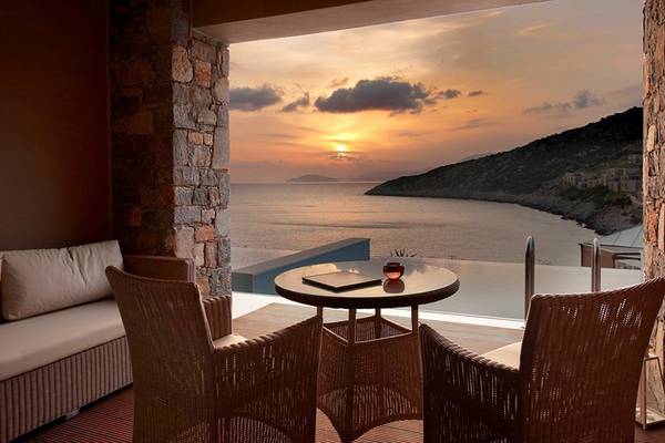 Terrasse des Daios Cove Luxury Resort & Villas mit Blick auf die untergehende Sonne und das Meer