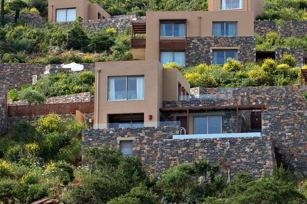Ein Luxusresort mit mehreren Steinhäusern, die auf einem Hügel liegen, umgeben von Pflanzen und Blumen.