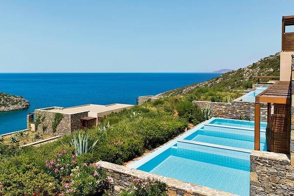 Außenpool des Daios Cove Luxury Resort mit Blick auf das Meer und die Landschaft.