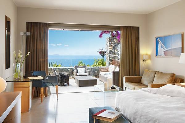 Suite im Daios Cove Luxury Resort & Villas mit Meerblick, Inneneinrichtung mit großem Bett und Couch.
