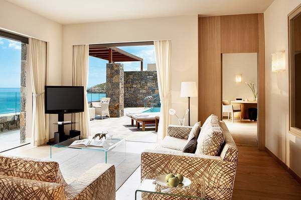 Wohnzimmer mit Meerblick im Daios Cove Resort & Villas, mit Sofas, Fernseher und Glastisch.