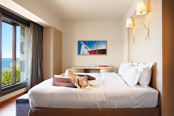 Zimmer im Daios Cove Luxury Resort & Villas mit Blick auf das Meer, inklusive Bett, Möbeln und Dekoration.