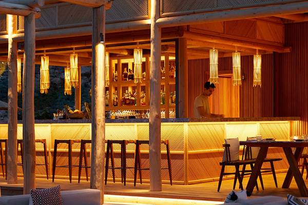Innenansicht der Bar im Daios Cove Luxury Resort & Villas mit Barkeeper und Tischen