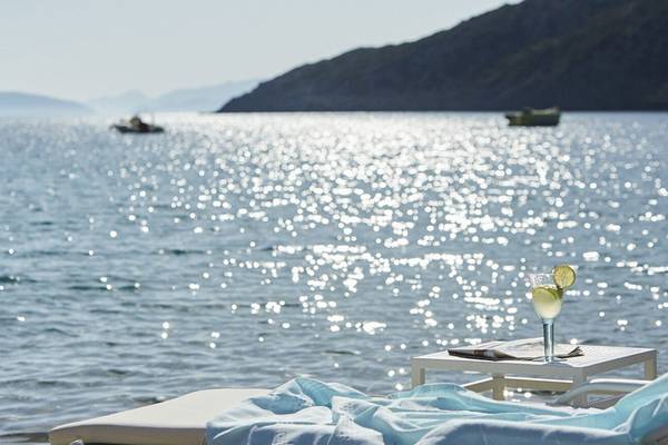 Meerblick vom Daios Cove Luxury Resort & Villas mit einem Glas und Liegestuhl