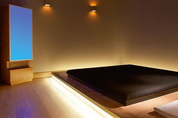 Ein Bett im Daios Cove Luxury Resort & Villas mit Lichtakzenten und einem Sideboard mit einem Bildschirm.