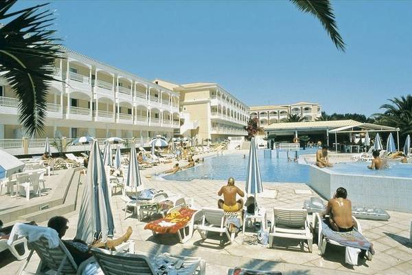 Poseidon Strandhotel mit Pool und Gästen auf Sonnenliegen im Freien