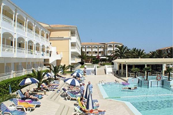 Außenbereich des Poseidon Beach Hotels mit Swimmingpool, Sonnenliegen und Sonnenschirmen.