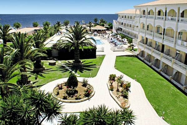Außenansicht des Poseidon Beach Hotels mit Pool, Rasen und Meer im Hintergrund