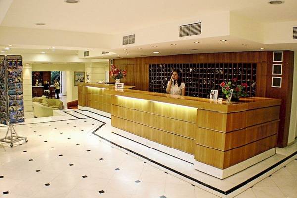 Empfangsbereich des Poseidon Beach Hotels mit Rezeptionistin am Schalter.
