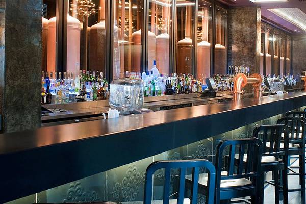 Innenansicht der Bar im Crowne Plaza Abu Dhabi Yas Island mit einer langen Theke, gefüllt mit verschiedenen Spirituosen und Cocktails.