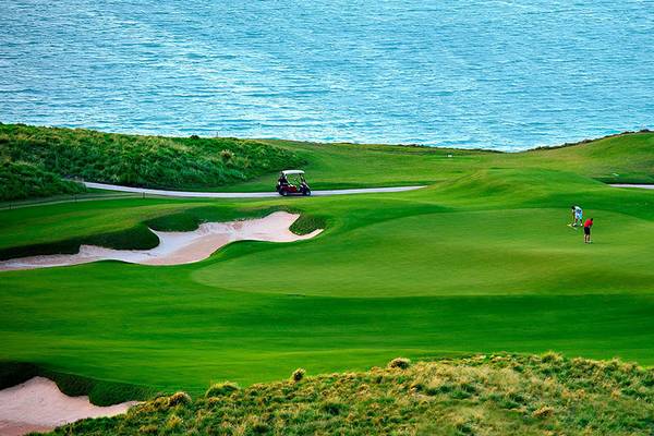 Golfplatz am Meer mit Golfwagen und Spielern