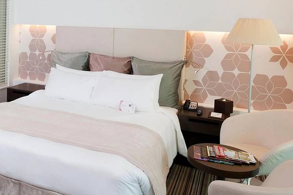 Innenansicht eines Hotelzimmers im Crowne Plaza Abu Dhabi Yas Island mit einem Doppelbett, Kissen, Nachttischen und einem Stuhl.