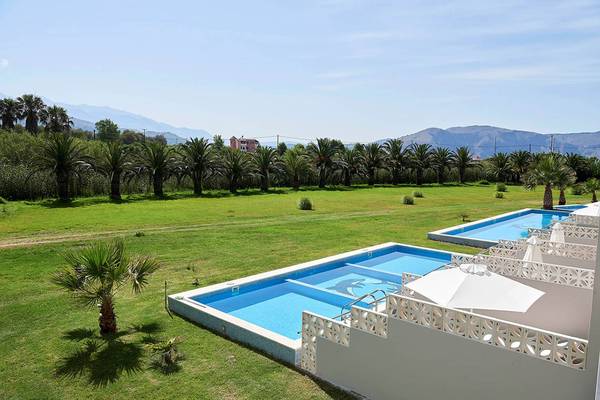 Außenbereich des Mythos Palace Resort & Spa mit zwei Swimmingpools und Palmen.