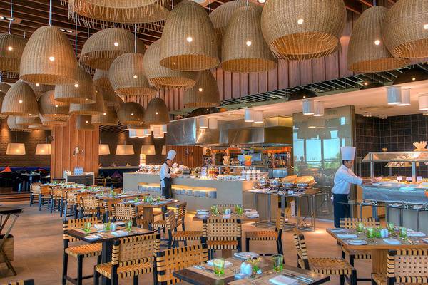Innenansicht des Crowne Plaza Abu Dhabi Yas Island Restaurants mit Köchen, die hinter einem Buffet stehen.