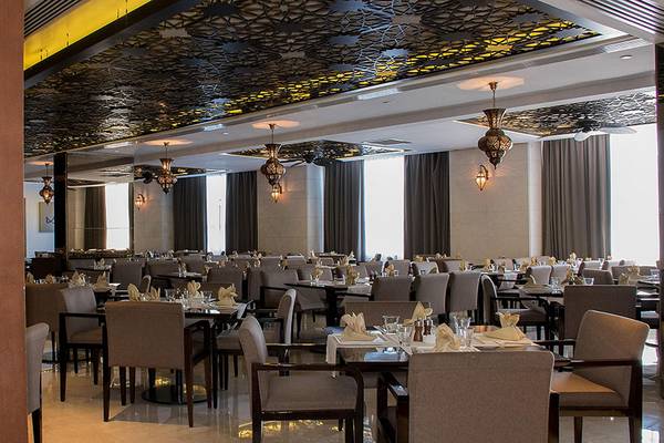 Innenansicht des Restaurants im Crowne Plaza Abu Dhabi Yas Island mit vielen gedeckten Tischen und dekorativen Deckenleuchten.