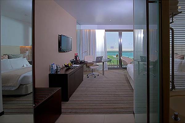 Hotelzimmer im Crowne Plaza Abu Dhabi Yas Island mit Blick auf den Ozean, Schreibtisch und Badewanne.