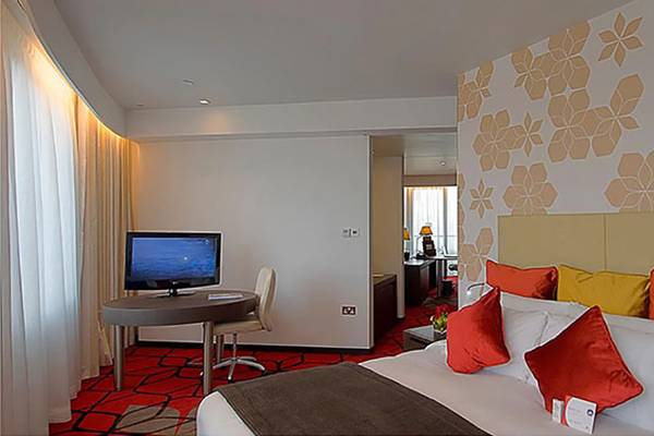 Ein geräumiges Hotelzimmer im Crowne Plaza Abu Dhabi Yas Island mit einem Bett, Tisch, Fernseher und eleganter Inneneinrichtung.