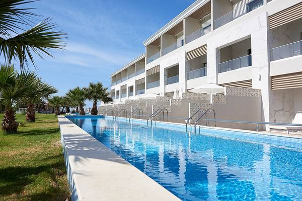 Außenpool des Mythos Palace Resort & Spa mit weißen Gebäuden und Palmen