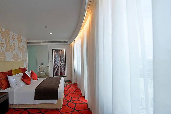 Hotelzimmer im Crowne Plaza Abu Dhabi Yas Island mit Doppelbett, roten Kissen und weißen Vorhängen.
