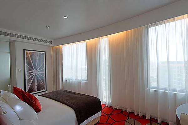 Hotelzimmer im Crowne Plaza Abu Dhabi Yas Island mit Bett, roten Kissen und großen Fenstern.