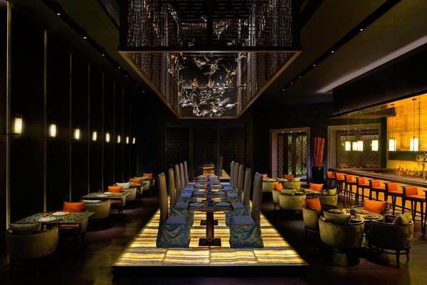 Innenraum des Atlantis The Palm Restaurants mit langen Tischen, Stühlen und einer dekorativen Decke.