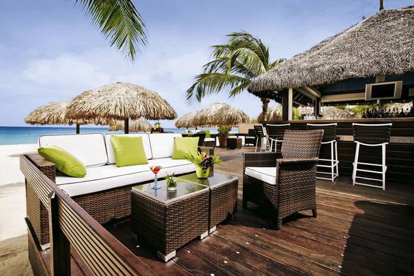 Loungebereich des Amsterdam Manor Beach Resort mit Strand, Stühlen und Tischen.