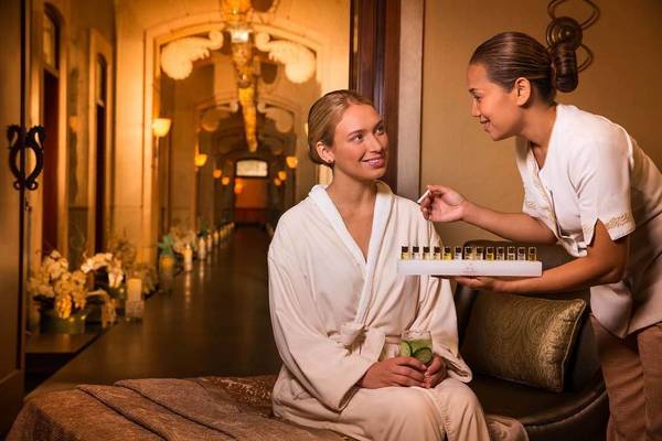 Zwei Frauen in Bademänteln im Hotel Atlantis The Palm, eine serviert der anderen ein Glas mit einer Limettenscheibe.