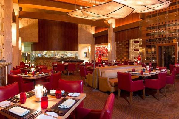 Innenansicht des Restaurants im Atlantis The Palm Hotel mit roten Stühlen und Tischen, Kerzen und Deckenleuchten.