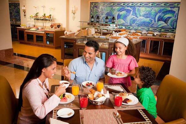 Eine Familie genießt ein Frühstück im Atlantis The Palm Hotel mit verschiedenen Speisen und Getränken.