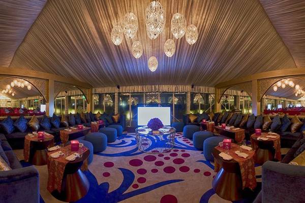 Innenbereich des Hotels Atlantis The Palm mit eleganten Möbeln, blauen und roten Teppichn, und großen Kronleuchtern.
