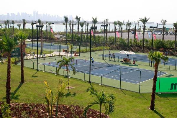 Tennisplatz im Atlantis The Palm Hotel mit mehreren Spielern und Palmen im Hintergrund.