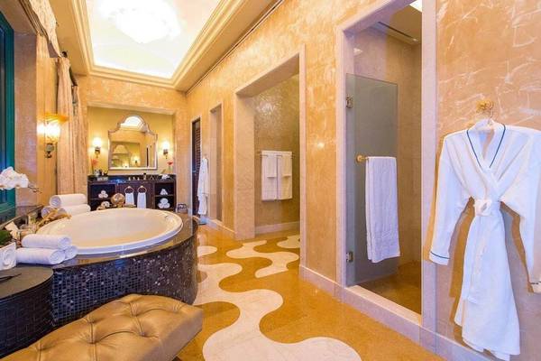 Luxus Badezimmer im Atlantis The Palm mit Badewanne, gemustertem Boden und weißen Handtüchern.