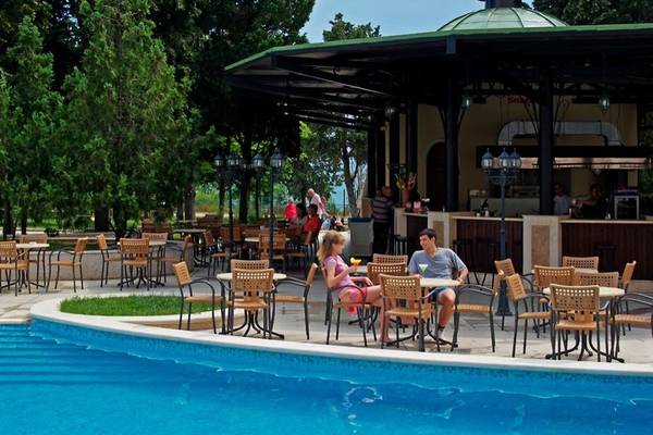 Gäste sitzen an einem Tisch vor einem Pool im Sol Nessebar Palace Hotel.