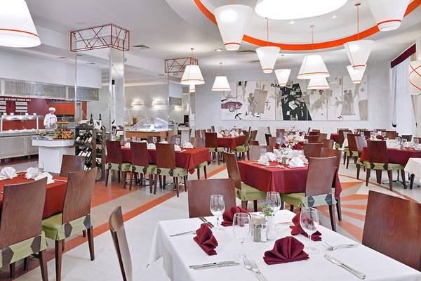 Innenansicht des Restaurants im Sol Nessebar Palace Hotel mit gedeckten Tischen und kochenden Köchen.