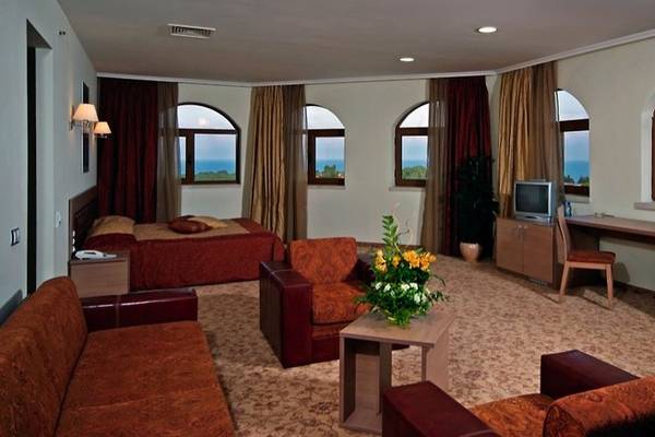 Hotelzimmer des Sol Nessebar Palace All Inclusive mit Bett, Sofa, Schreibtisch und Aussicht auf den Ozean.