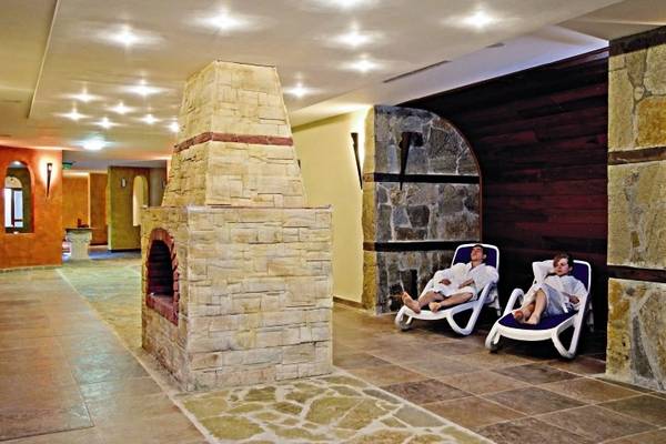 Relaxationsbereich im Sol Nessebar Palace All Inclusive Hotel mit zwei Personen auf Liegen neben einem Steinkamin