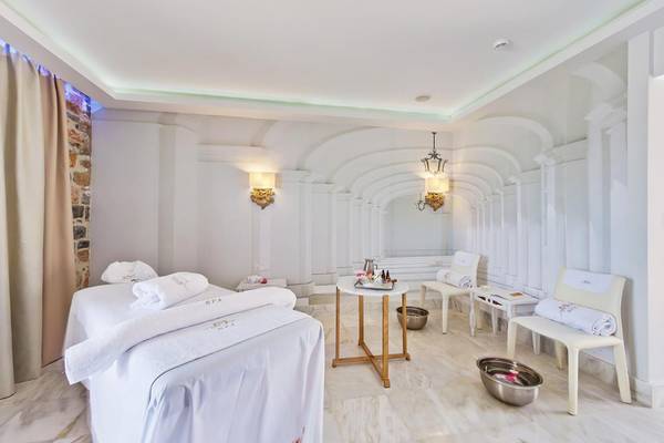 Spa-Behandlungsraum im Royal Marmin Bay Boutique Hotel mit weißen Möbeln und Marmorboden.