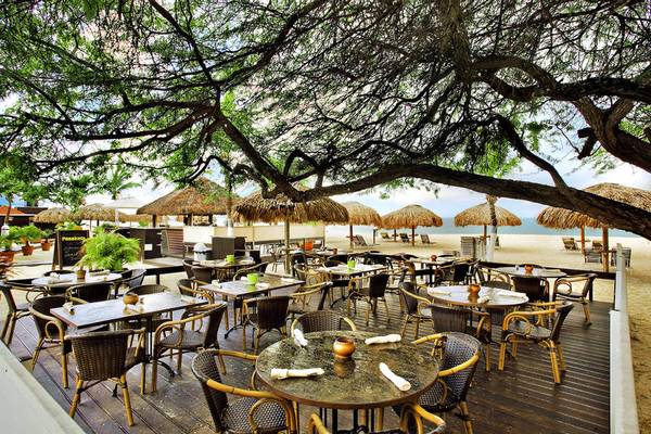 Terrasse des Amsterdam Manor Beach Resorts mit Tischen, Stühlen und Strohhüten