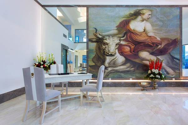 Royal Marmin Bay Boutique Hotel Innenraum mit Tisch, Stühlen und großer Wandmalerei.