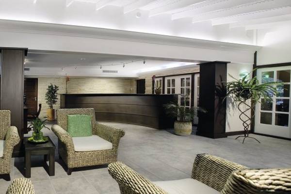 Lobby des Amsterdam Manor Beach Resorts mit zwei Weidenstühlen, einem Tisch und Pflanzen.