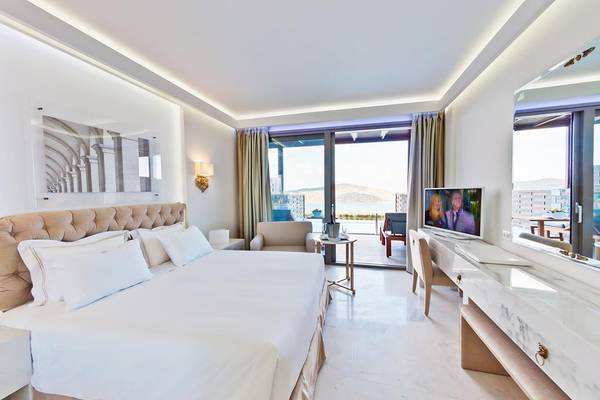 Ein elegantes Schlafzimmer im Royal Marmin Bay Boutique Hotel mit einem großen Bett und einer Aussicht auf das Meer.
