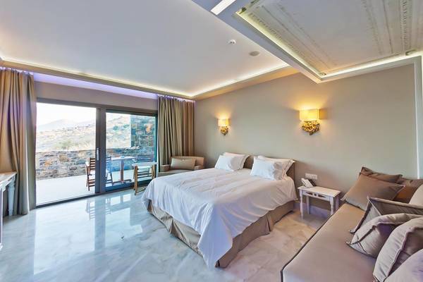 Ein elegantes Schlafzimmer im Royal Marmin Bay Boutique Hotel mit Blick auf eine Terrasse und Berge.